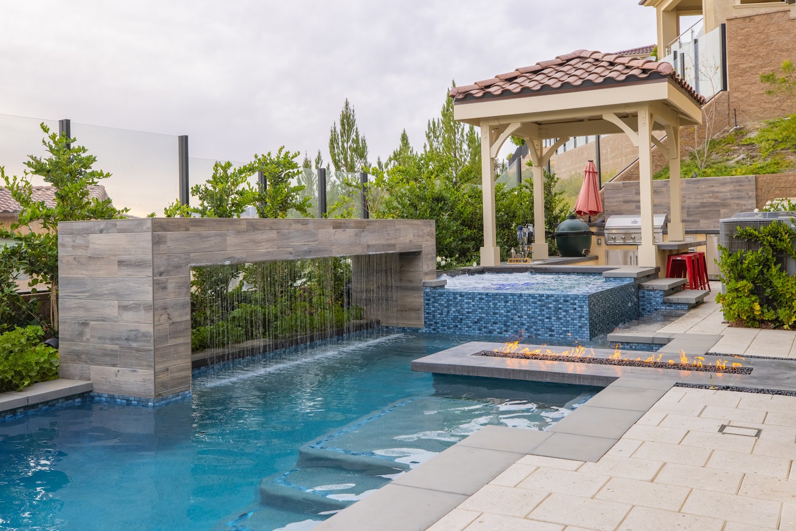 Contemporary pool design with waterfall feature and perimeter overflow spa