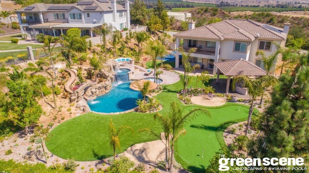 A bad-ass backyard has stunning features like a pool, slide, faux golf turf, spa, and outdoor kitchen