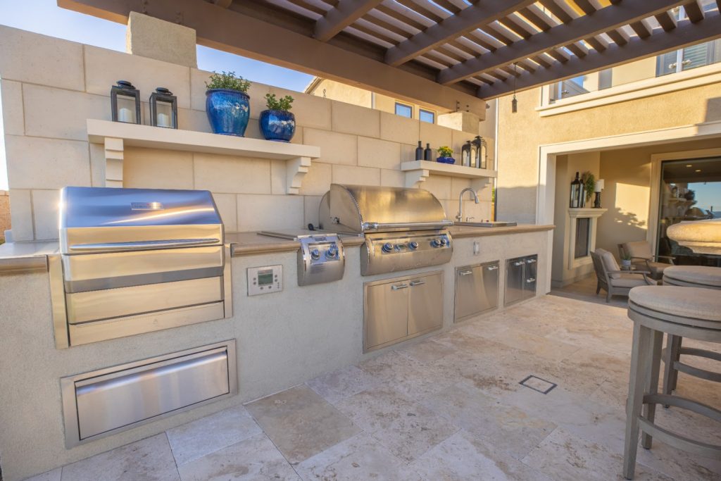 Outdoor kitchen with grill, cooler, stovetop, sink, and outdoor seating