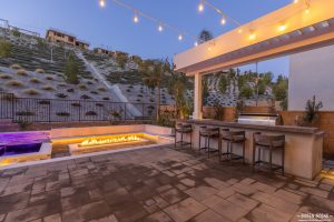 Outdoor kitchen and patio with bistro lights and fire pit